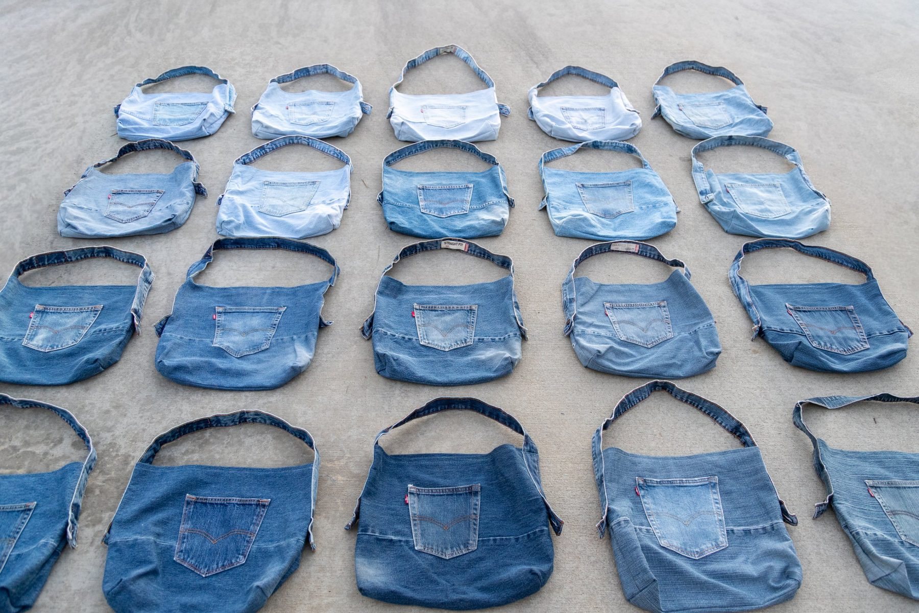 Rows of one-of-one denim bags laid out on concrete